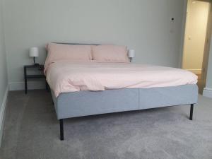 Elle comprend un grand lit avec des draps et des oreillers roses. dans l'établissement Beautiful New built 2 bedroom apartment, à Purley
