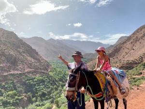 a man and a girl riding a horse in the mountains at Dar Imoughlad in Marrakech