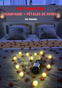 Una cama con velas y una botella de vino y rosas. en LOFT Jardin et Spa, en Bressuire
