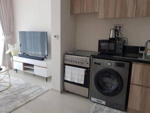 a kitchen with a washing machine and a tv at Cosy 1 bedroom in Damac Hills in Dubai