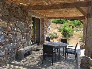 einen Tisch und Stühle auf einer Terrasse mit einer Steinmauer in der Unterkunft Casa Lysandra in Serra-di-Ferro