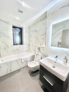 La salle de bains est pourvue d'un lavabo, de toilettes et d'une baignoire. dans l'établissement Queens Luxury Apartments Wembley Stadium - London, à Londres