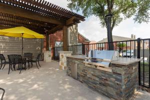 a patio with a grill with chairs and an umbrella at The Val's Place in Houston