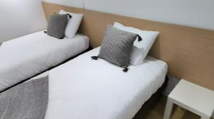 two beds in a room with white and gray pillows at Suitel Pombal in Pombal