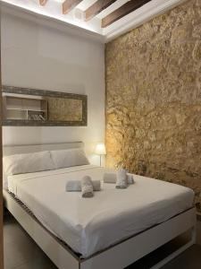 1 dormitorio con cama blanca y pared de piedra en DES Rustic Center, en Alicante