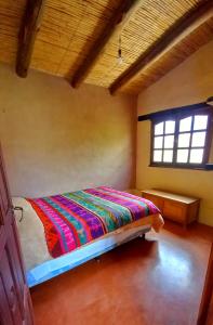 1 dormitorio con 1 cama en una habitación con ventana en MAMAICUNA CABAÑA en Tilcara