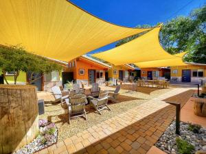 a patio with tables and chairs under a large yellow umbrella at Downtown Kokopelli West 5 - Newly Remodeled Stylish Studio in Moab