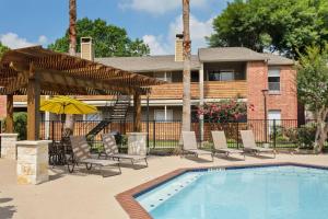 una piscina con sedie e ombrellone e una casa di The Val's Place a Houston