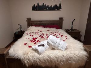 a bed with a white blanket and red flowers on it at Romantic Luxury Retreat with Private Sauna & Spa, Pet Friendly, Elkside Hideout B&B in Canmore
