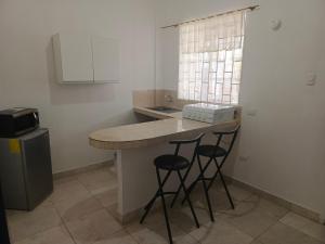 a kitchen with two stools at a counter with a sink at Sol de Ayangue in Ayangue