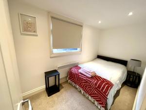 a small bedroom with a bed and a window at Central Morden, Westfield, close to Tube station in London