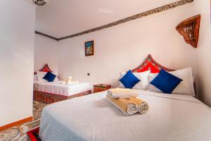 een slaapkamer met 2 bedden met blauwe en rode kussens bij Hotel Chefchaouen in Chefchaouene