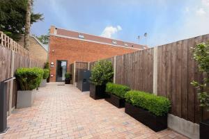 a brickicked walkway with a wooden fence and plants at D & D Luxury Apartments in Stanmore