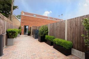 una pasarela de ladrillos con una valla de madera y plantas en D & D Luxury Apartments, en Stanmore