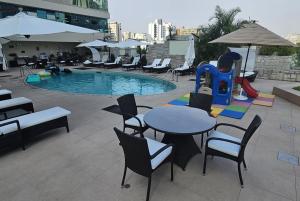 un patio con mesa, sillas y piscina en Delfines Hotel & Convention Center en Lima