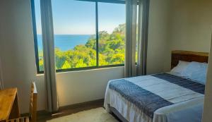 a bedroom with a bed and a large window at Sunshine Sanctuary Boutique Jungle Lodge in Montezuma