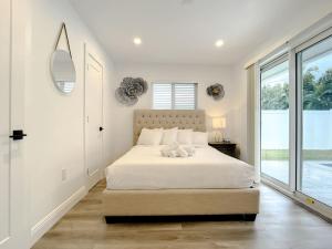 a white bedroom with a bed and a large window at Luxe Home - Heated Pool I 5 min to Beach I BBQ Grill in Fort Lauderdale
