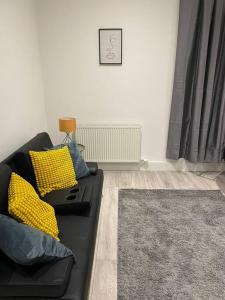 a living room with a black couch with yellow pillows at Maidstone Modern Flat High Street in Kent