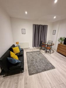 a living room with a black couch and a table at Maidstone Modern Flat High Street in Kent