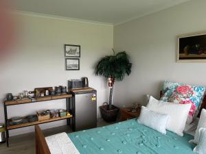 Beauty at whitbourne في أوتوروهانغا: غرفة نوم فيها سرير وزرع