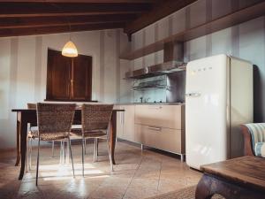 La cuisine est équipée d'une table, de chaises et d'un réfrigérateur. dans l'établissement Corte Uccellanda Relais, à Monzambano