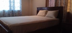 a bed with white sheets and pillows next to a window at Residencial derosas 