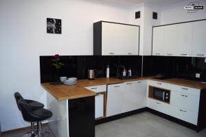 a kitchen with white cabinets and a desk with a chair at White & Black Apartament in Ełk