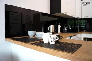 un bancone della cucina con due tazze da caffè sopra di White & Black Apartament a Ełk Altre 14 foto