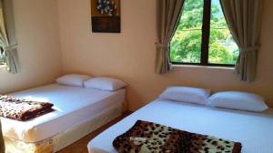 a bedroom with two beds and a window at FERRINGHI HOUSE with POOL, BBQ SET, 5 MINUTES WALK to BEACH in Batu Ferringhi