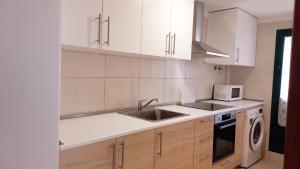 a kitchen with white cabinets and a sink and a microwave at Sunny in Antigua