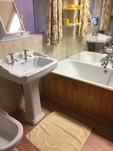 een badkamer met een wastafel en een bad bij Lowry House Hotel in Great Barr in Birmingham