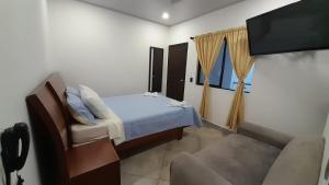 a bedroom with a bed and a tv and a couch at Katara Boutique Hotel in Mariquita