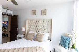 a white bedroom with a large white bed and a chair at Luxury 3BR Penthouse in Astria 1407 in Tegucigalpa