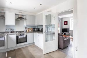 Captivating 2 bedroom home with jacuzzi and conservatory في هاميلتون: مطبخ مع دواليب بيضاء وغرفة معيشة