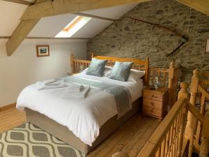 a bedroom with a large bed and a stone wall at Tanyresgair Cottages in Aberystwyth