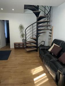 un salon avec un canapé et un escalier en colimaçon dans l'établissement Maison de ville, à Vitry-sur-Seine