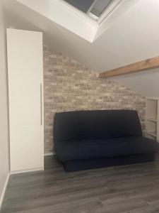 - une chambre avec un lit noir et un mur en briques dans l'établissement Maison de ville, à Vitry-sur-Seine 2 autres photos