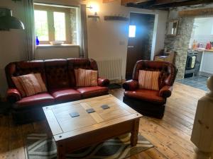 a living room with two leather couches and a coffee table at Tanyresgair Cottages in Aberystwyth