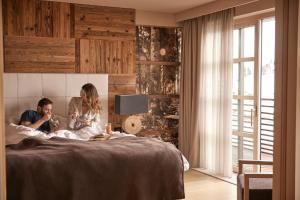 a man and a woman sitting on a bed at COMO Alpina Dolomites in Alpe di Siusi