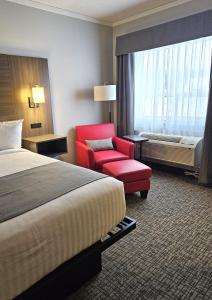 a hotel room with a bed and a red chair at The Kanata by BCMInns - Hinton in Hinton