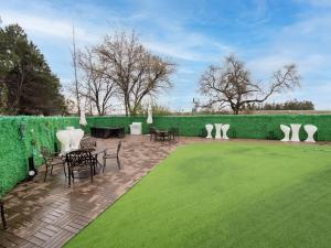 een patio met stoelen en tafels en een groene heg bij Baymont by Wyndham Anderson in Anderson