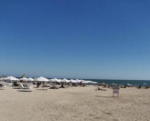 einen Strand mit vielen weißen Sonnenschirmen und Menschen darauf in der Unterkunft Apartment DEVA in Baltschik