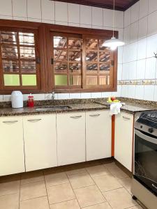 a kitchen with white cabinets and a stove at casa ilha bela in Ilhabela