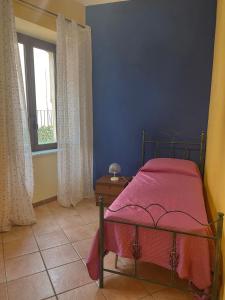 a bedroom with a bed with a pink blanket and a window at Peperoni House - Sea and Mountain Experience in San Marco Argentano +11 photos