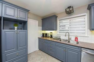 een keuken met blauwe kasten en een wastafel bij Discover Your Home Away From Home Near YYZ Airport in Mississauga