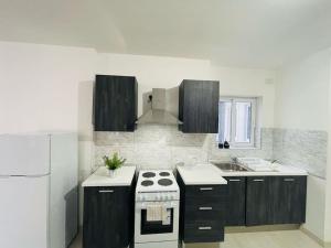 een keuken met zwarte kasten en een witte kookplaat bij Coral Cove Comfort Room 1 in St Paul's Bay