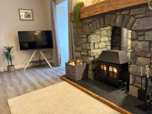 a living room with a stone fireplace with a television at Ty Cerrig in Dyffryn