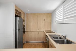 a kitchen with wooden cabinets and a stainless steel refrigerator at Bayona Apartment 2, Little Cove in Noosa Heads