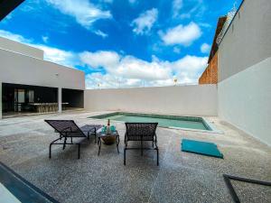 eine Terrasse mit 2 Stühlen und einem Pool in der Unterkunft Casa butique veraneios 2 in Caldas Novas