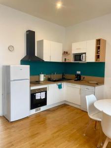a kitchen with a white refrigerator and a table at Madini-Breizh :T3 cœur de ville in Lannion +6 photos